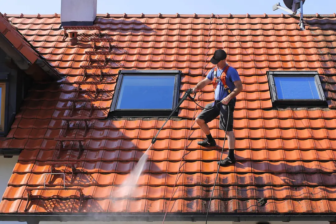 Entretien de toiture : opération de nettoyage d'un toit en tuiles